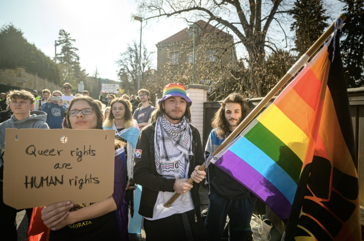 Lidé pochodující s transparentem Queer rights are human rights Lidé pochodující s transparentem Queer rights are human rights